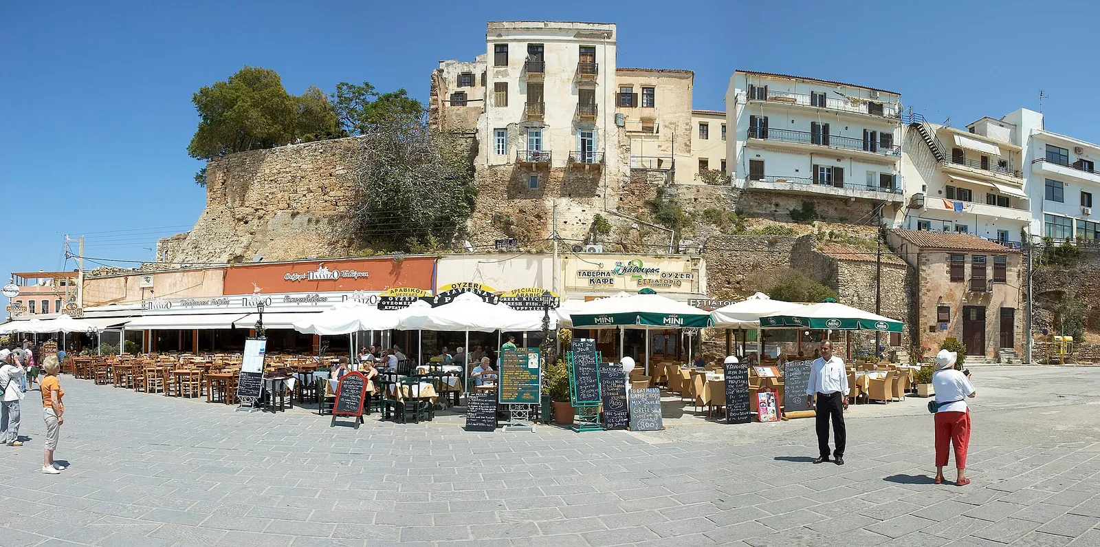 טיילת הנמל הישן של חאניה בכרתים יוון עם טברנות ובתי קפה למרגלות בתי העיר העתיקה
