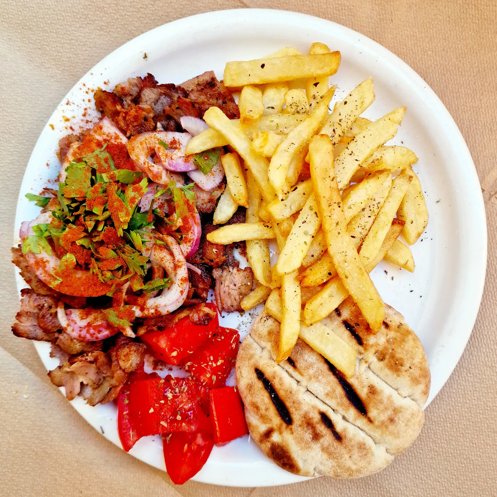 צלחת גירוס עם צ׳יפס פיתה ועגבניות במסעדה עממית ביוון, אוכל זול וטעים שחוסך בתקציב הטיול