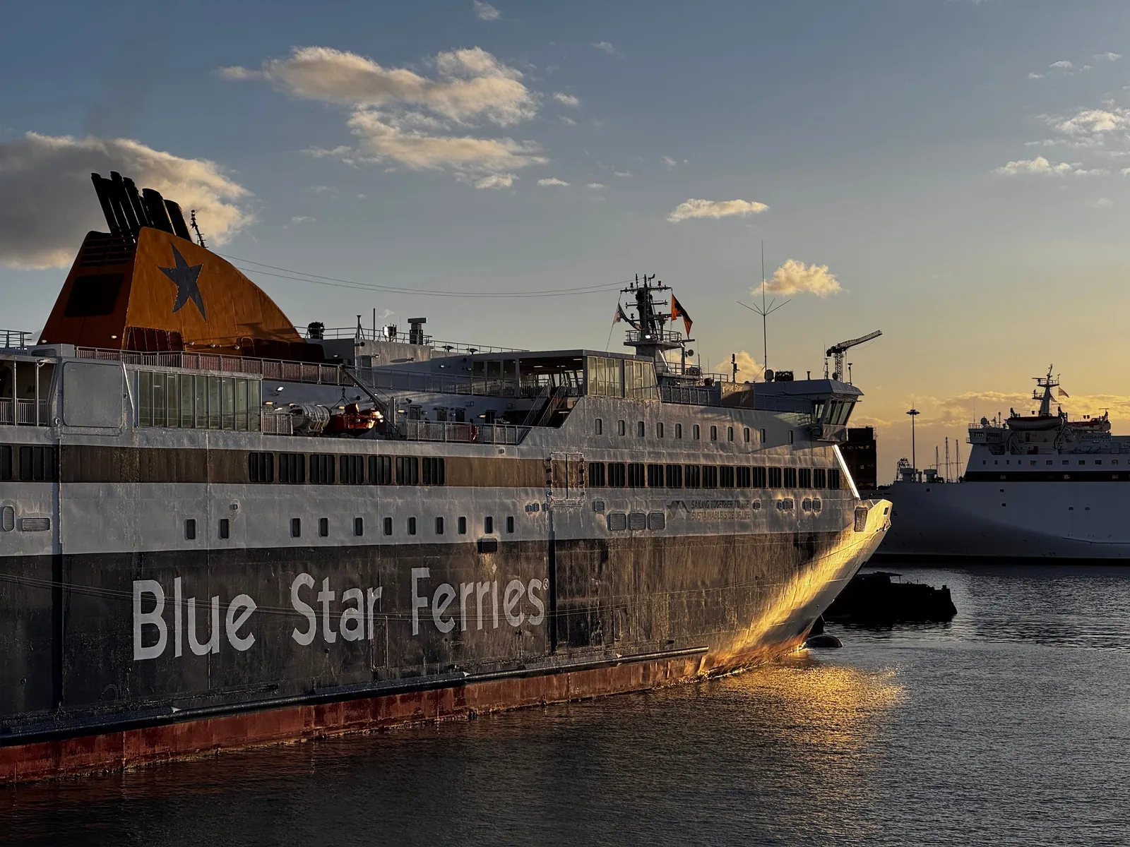 מעבורת של Blue Star Ferries עוגנת בנמל יווני באור שעת הזהב