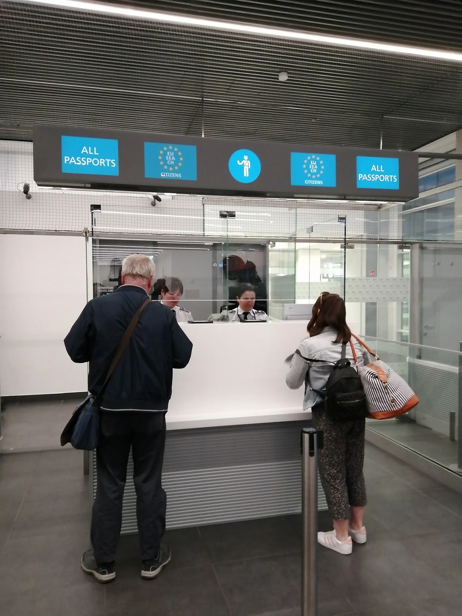 נוסעים בעמדת ביקורת דרכונים בשדה תעופה באיחוד האירופי עם שלטי מסלול לאזרחי האיחוד, כמו בכניסה ליוון