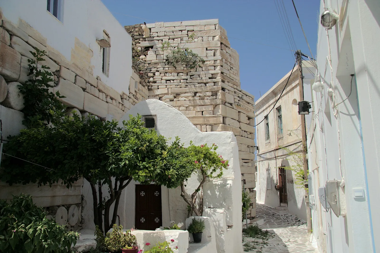 סמטה בעיר העתיקה של פאריקיה בפארוס עם חומת הקסטרו הבנויה מאבני שיש עתיקות, יוון