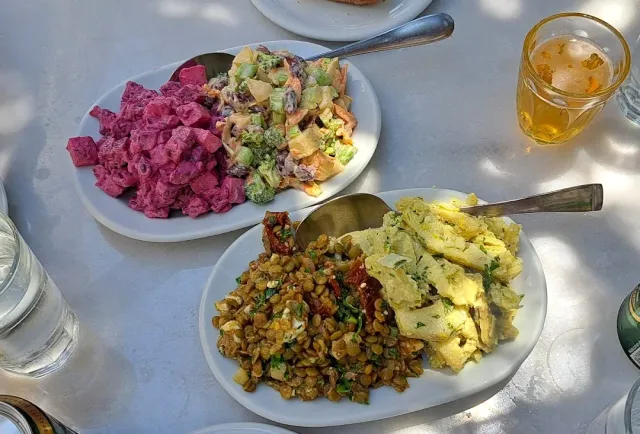 שלוש צלחות סלטים על שולחן אבן, ולצדן כוס משקה קר