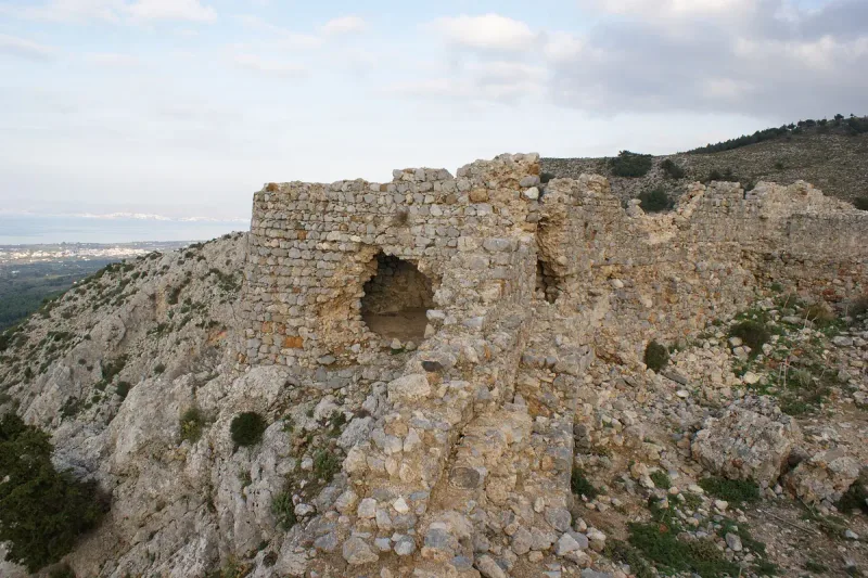 חומות אבן מתפוררות של מבצר פיילי העתיקה על גבעה מכוסת שיחים בקוס