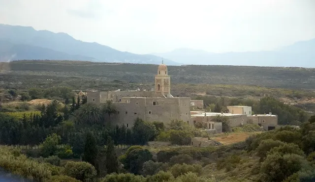 מנזר מבוצר עם מגדל פעמונים גבוה, עומד בודד בנוף גבעות יבש