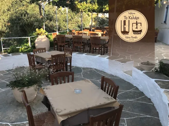 חצר אבן עם שולחנות עץ, כד חרס גדול ושלט עגול על הקיר