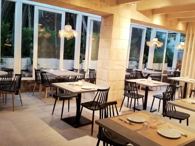 אולם מודרני עם עמודי אבן, כיסאות שחורים ומנורות קש תלויות