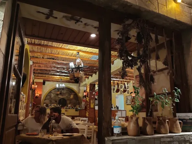 פנים מואר עם תקרת קנים, צרורות עשבים תלויים וכדי חרס על מדף