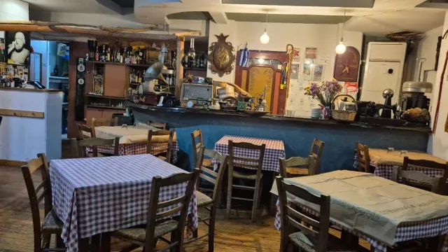 חלל כפרי עם דלפק עץ עמוס חפצים, מפות משובצות אדומות וכיסאות עץ