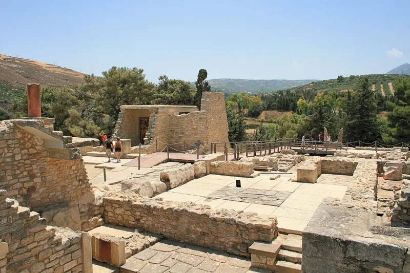חפירות של ארמון עתיק עם קירות אבן ומדרגות, וגבעות ירוקות ברקע