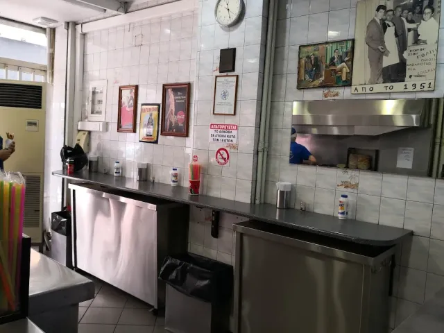 מטבח מרוצף קרמיקה לבנה עם דלפקי נירוסטה ותצלומים ישנים ממוסגרים
