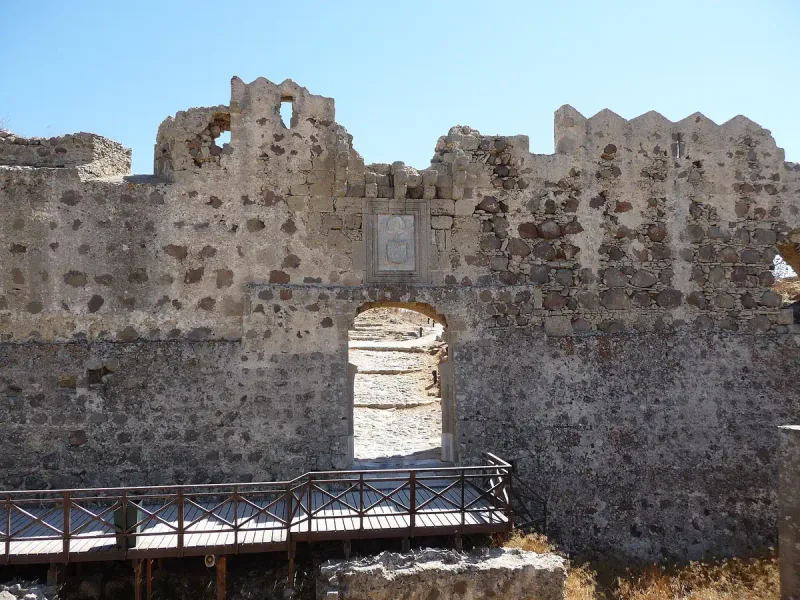 שער כניסה מקומר בחומת האבן של מבצר אנטימאכיה בקוס, עם גשר עץ קטן לפניו