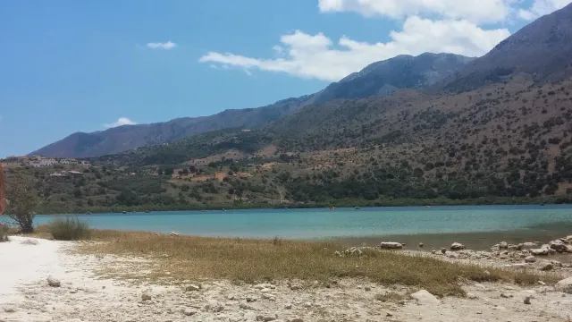 אגם מים ירקרקים מוקף הרים, ורצועת חול בקדמת התמונה
