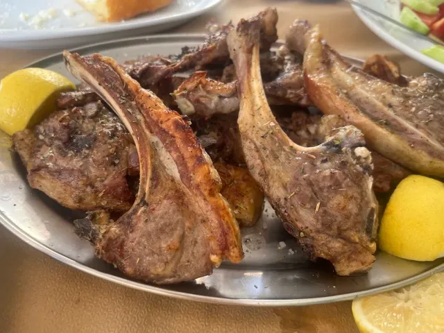 מגש מתכת עם צלעות טלה צלויות ופלחי לימון בקצוות