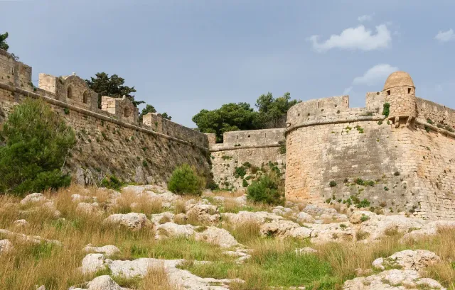 חומות מבצר אבן ארוכות עם מגדלי הגנה, על גבעה מעל העיר