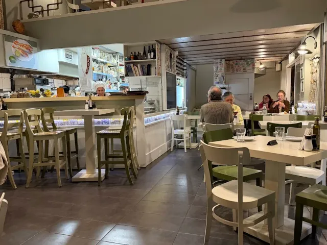 אולם בהיר עם דלפק, שרפרפים גבוהים וסועדים יושבים בשולחנות
