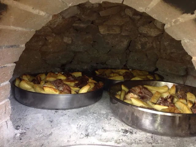 תבניות של בשר ותפוחי אדמה צלויים בתוך תנור אבן מסורתי