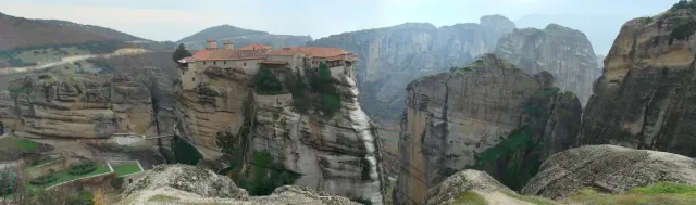 מנזר אבן על ראש עמוד סלע, ומצוקים ועמק מסביבו