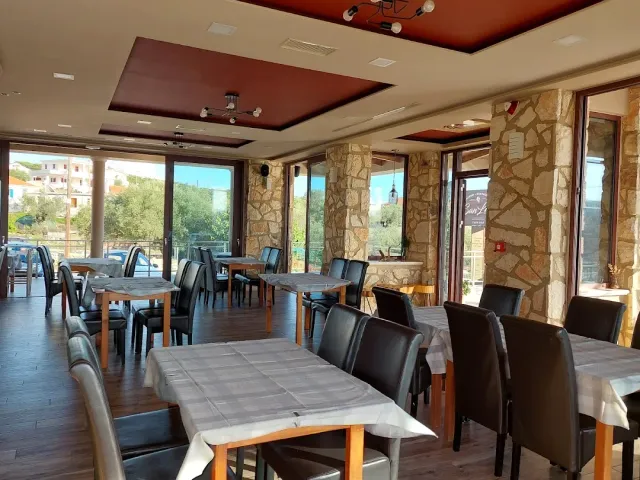 אולם פנימי עם שולחנות עץ, כיסאות כהים ועמודי אבן מול חלונות גדולים