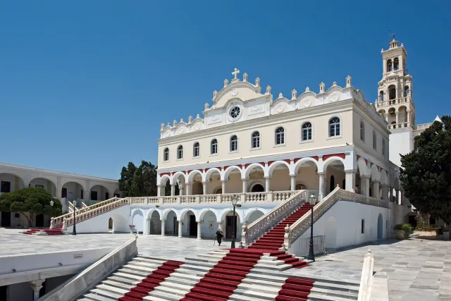 כנסייה לבנה עם קשתות ומגדל פעמונים, ומרבד אדום עולה במדרגות