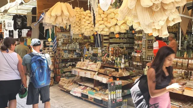חנות בשוק עם ספוגים טבעיים תלויים, מדפי מוצרים ומטיילים במעבר