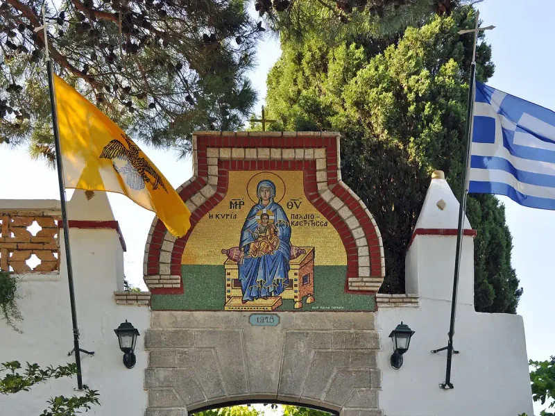 שער מנזר מסויד ובו איקונה בפסיפס ודגלים מתנופפים לצדו