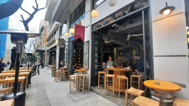 חזית בר פתוחה לרחוב עם שרפרפי עץ, חביות כשולחנות ותנורי חימום על המדרכה